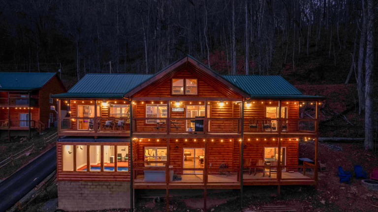 Two-story log cabin with lit interiors and multiple decks for group stays.