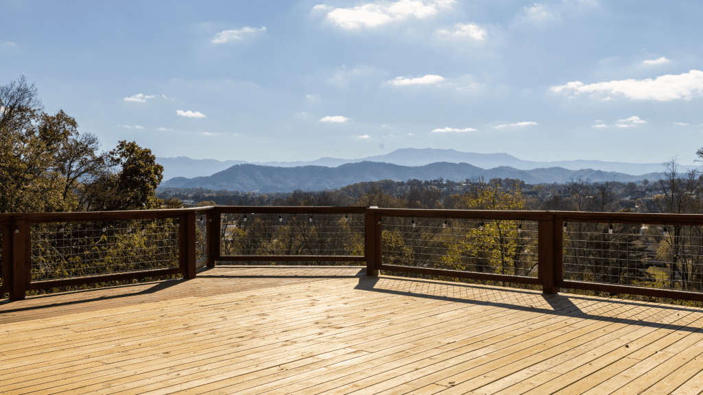 Elevated deck with wooden railings overlooking Smoky Mountains under a clear blue sky in Cherokee.