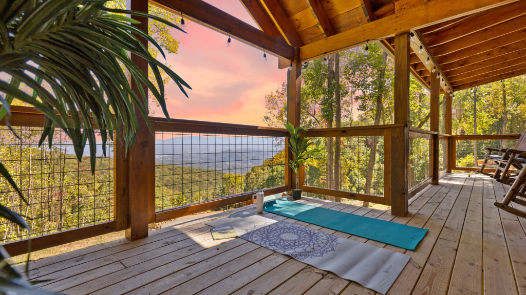 Yoga mats on a private deck with scenic mountain views, surrounded by trees.