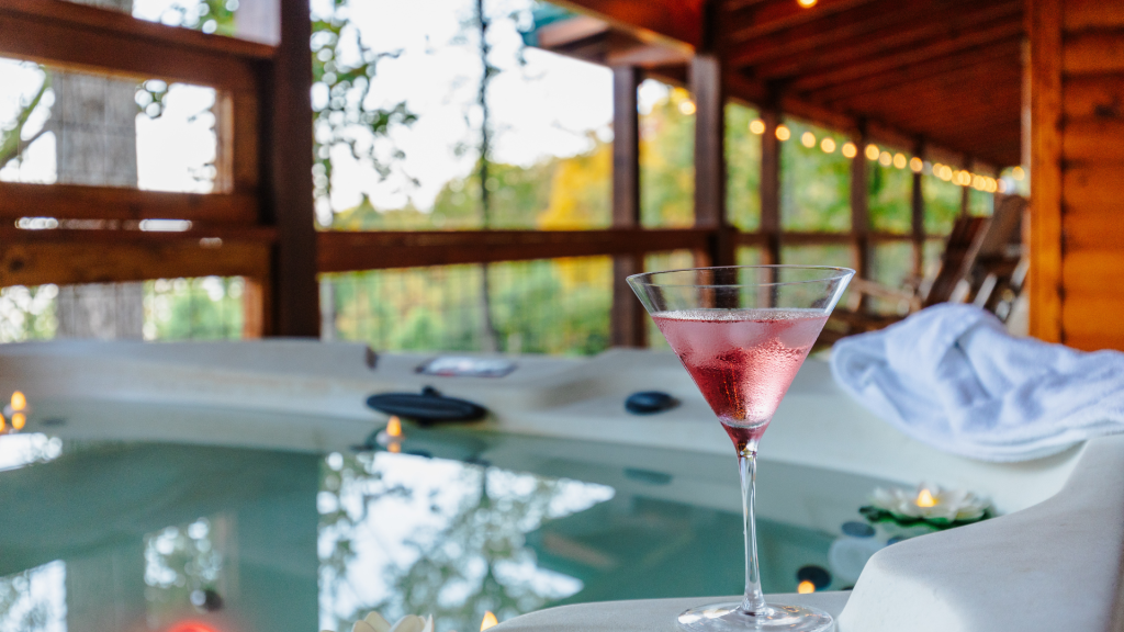 Private hot tub on a cabin deck surrounded by the smoky mountains with a martini glass.