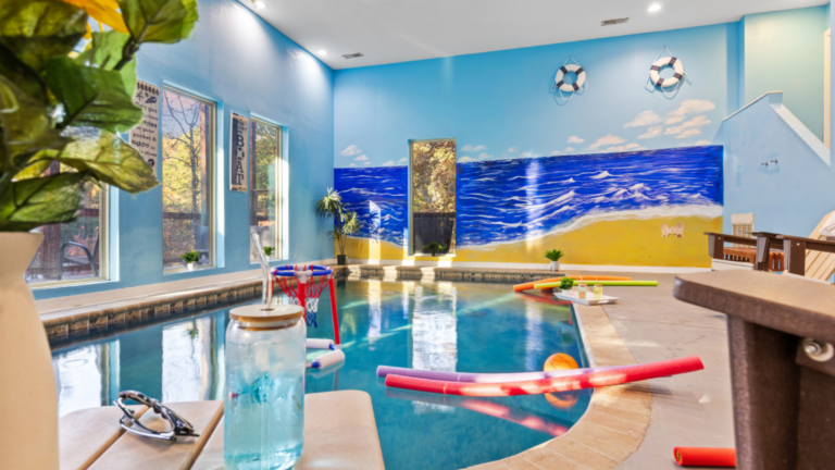 Indoor pool with a beach mural, pool toys, and seating area.