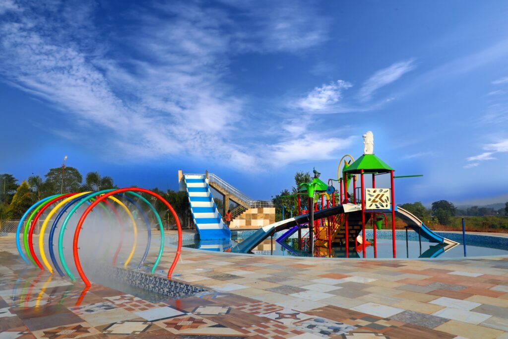 A colorful outdoor water playground at Soaky Mountain Waterpark features slides, climbing structures, and water spray arches under a bright blue sky, with tiled flooring and greenery—perfect for any travel guide.